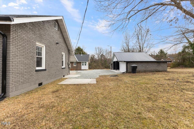 view of side of property with an outbuilding, a yard, and a patio