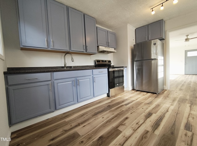 kitchen featuring sink, ceiling fan, appliances with stainless steel finishes, light hardwood / wood-style floors, and a textured ceiling