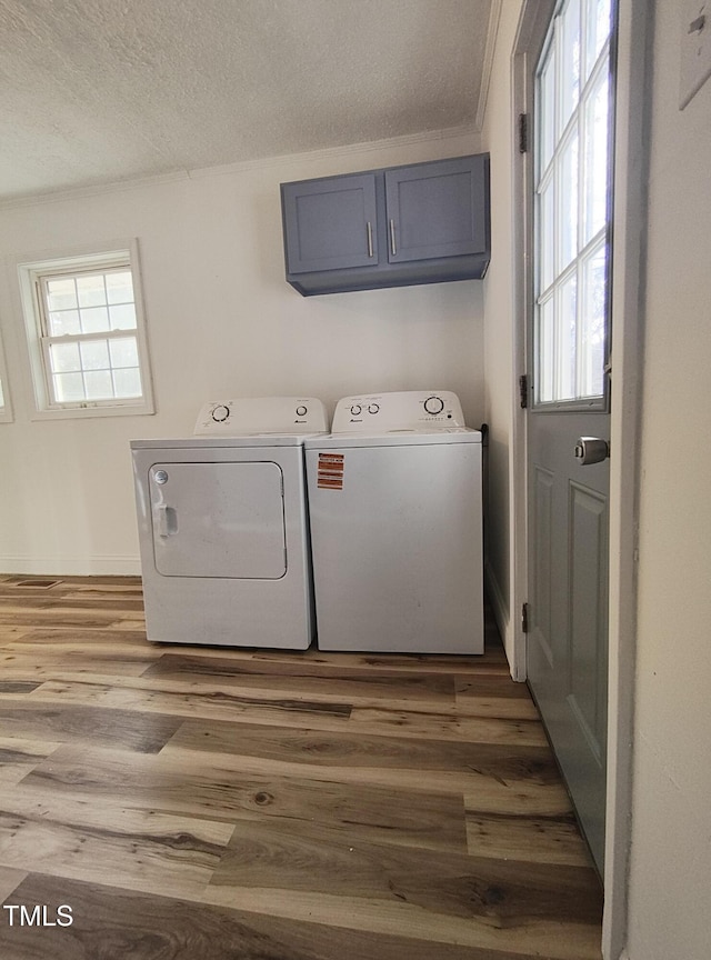 laundry room featuring hardwood / wood-style flooring, cabinets, separate washer and dryer, and a textured ceiling