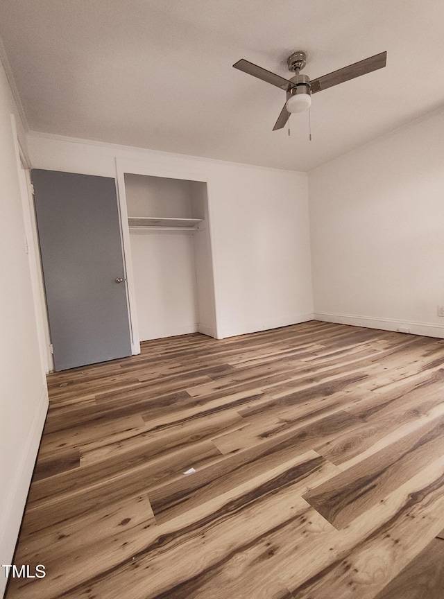 unfurnished bedroom featuring ceiling fan, hardwood / wood-style floors, and a closet