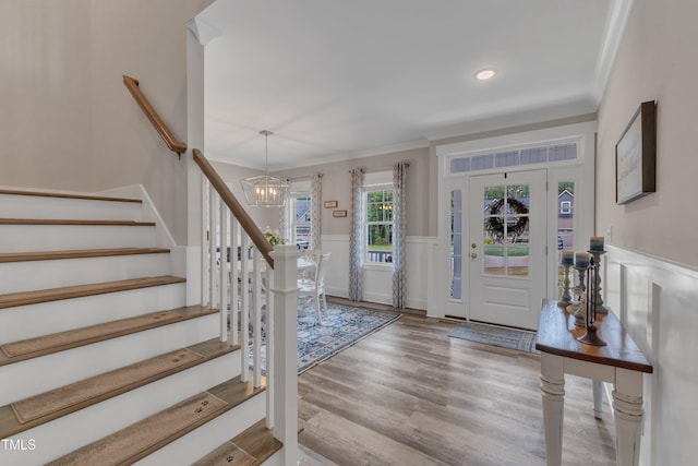 foyer entrance with crown molding, a chandelier, and light hardwood / wood-style flooring