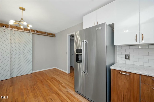 kitchen with pendant lighting, white cabinetry, tasteful backsplash, light stone countertops, and high end refrigerator