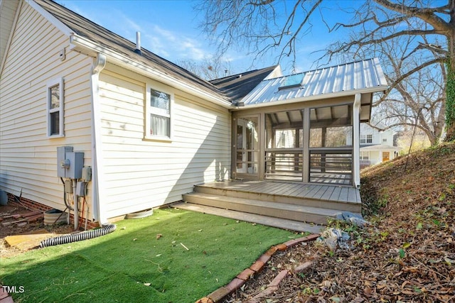 back of house with a wooden deck, a sunroom, and a lawn