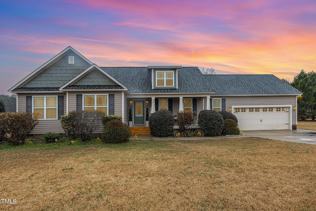 view of front facade featuring a garage, a lawn, and a porch