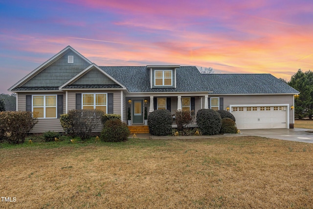 view of front of home with a garage, a porch, and a lawn