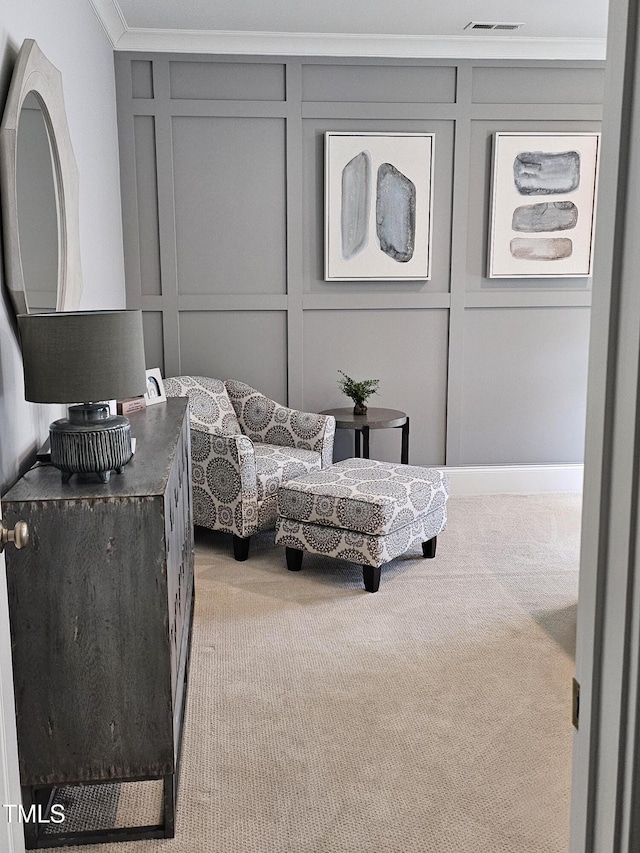 sitting room with light carpet, ornamental molding, visible vents, and a decorative wall