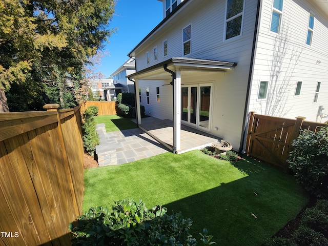 rear view of house featuring a fenced backyard, a lawn, and a patio