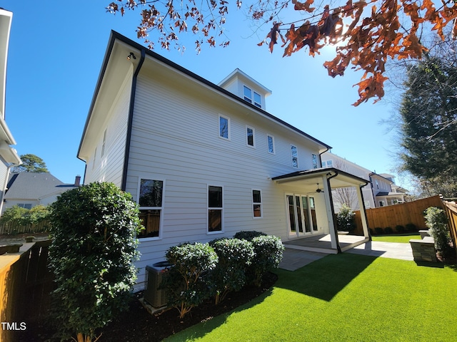 back of house featuring central AC unit, a ceiling fan, a patio, a fenced backyard, and a yard