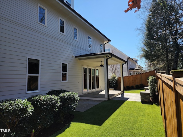 rear view of property featuring ceiling fan, a fenced backyard, a patio, and a lawn