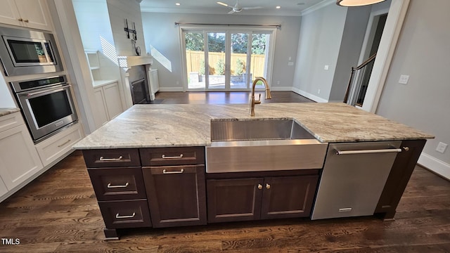 kitchen with white cabinets, light stone counters, stainless steel appliances, and a sink