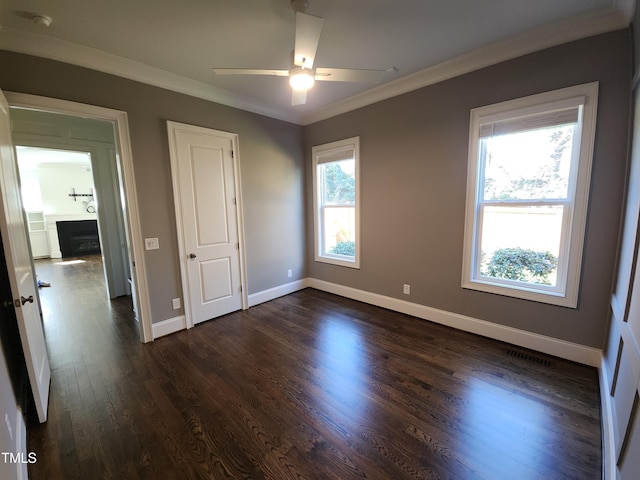 unfurnished bedroom featuring ornamental molding, a fireplace, baseboards, and dark wood-style floors