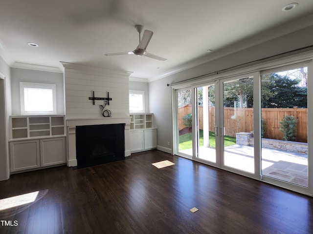 unfurnished living room featuring ornamental molding, a fireplace, dark wood finished floors, and a wealth of natural light