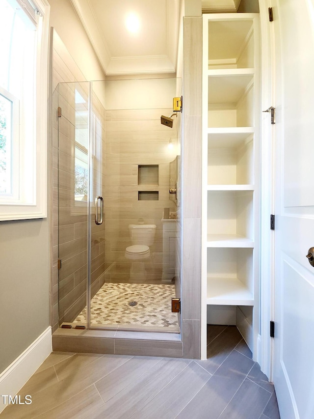 full bath with built in shelves, toilet, baseboards, a stall shower, and crown molding