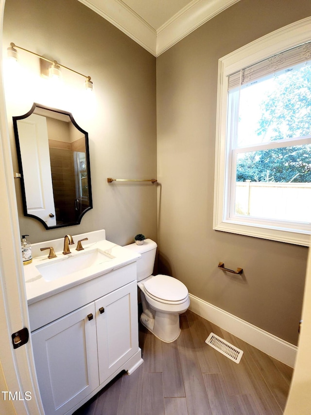 bathroom with baseboards, visible vents, wood finished floors, crown molding, and vanity