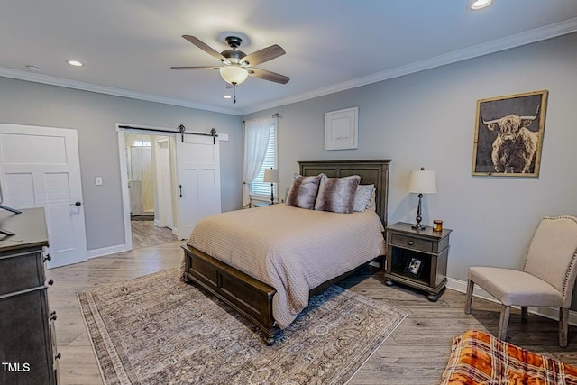 bedroom with crown molding, ceiling fan, a barn door, and light hardwood / wood-style flooring