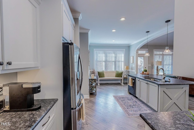 kitchen with sink, dark stone countertops, stainless steel appliances, white cabinets, and decorative light fixtures