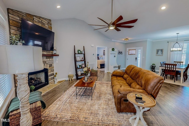 living room featuring a stone fireplace, lofted ceiling, ceiling fan, and light hardwood / wood-style flooring