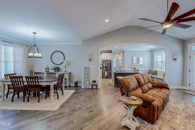 living room with vaulted ceiling, wood-type flooring, crown molding, and sink