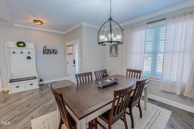 dining space featuring crown molding, wood-type flooring, and a chandelier