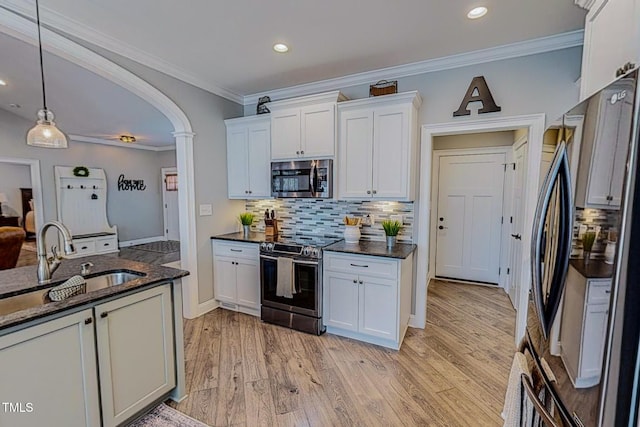 kitchen featuring appliances with stainless steel finishes, pendant lighting, white cabinetry, sink, and light wood-type flooring