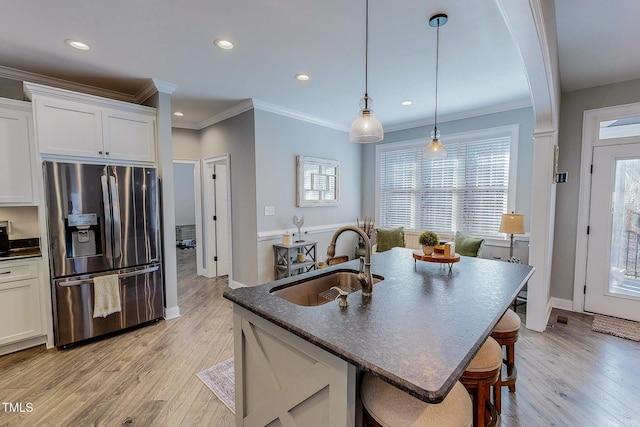 kitchen with sink, white cabinets, a kitchen breakfast bar, and stainless steel fridge with ice dispenser