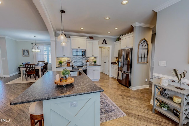 kitchen with stainless steel appliances, a kitchen island with sink, sink, and white cabinets