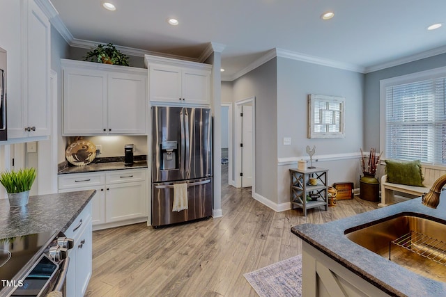 kitchen with sink, dark stone countertops, white cabinets, stainless steel appliances, and light wood-type flooring