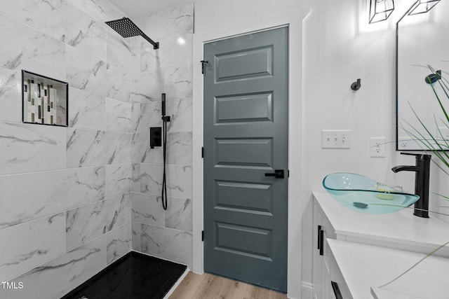 bathroom with a tile shower, hardwood / wood-style floors, and vanity