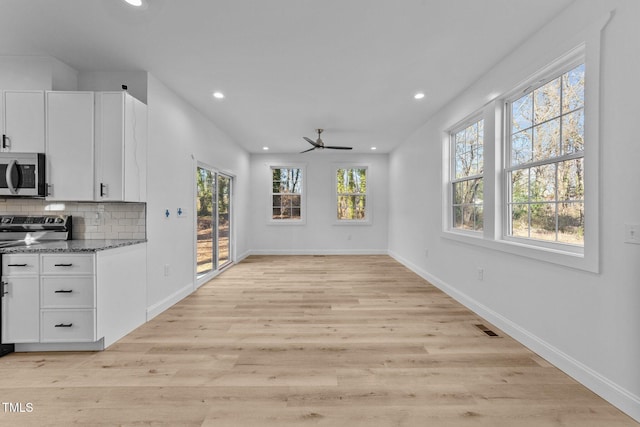 unfurnished dining area with a healthy amount of sunlight, ceiling fan, and light hardwood / wood-style flooring