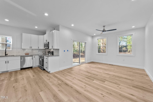 kitchen featuring sink, white cabinetry, stainless steel appliances, tasteful backsplash, and light stone countertops