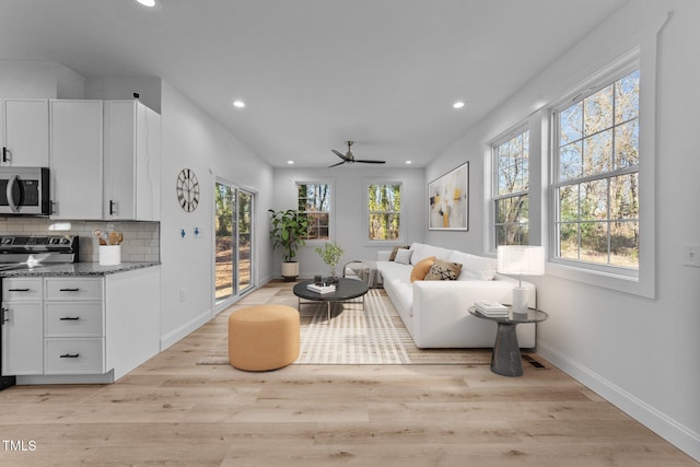 living room with plenty of natural light, ceiling fan, and light hardwood / wood-style flooring