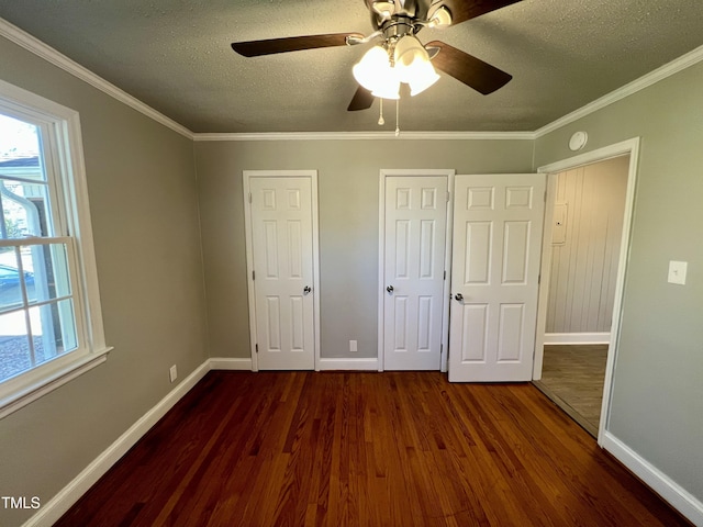 unfurnished bedroom with multiple windows, crown molding, dark hardwood / wood-style floors, and a textured ceiling