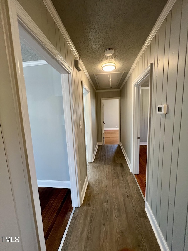 hall featuring ornamental molding, dark wood-type flooring, and a textured ceiling