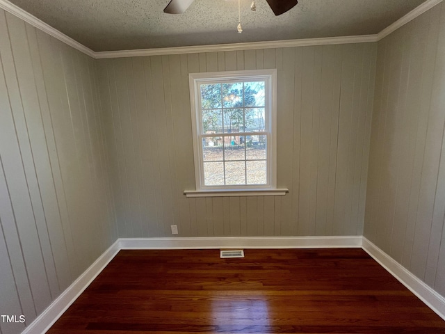 empty room featuring crown molding, dark wood-type flooring, a textured ceiling, and ceiling fan