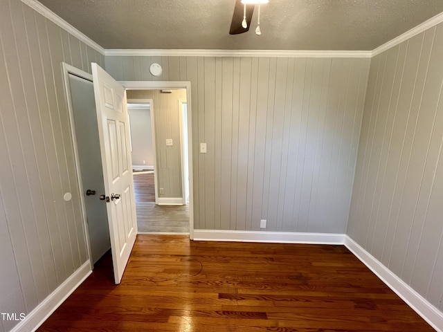 empty room with ornamental molding, wood-type flooring, and a textured ceiling