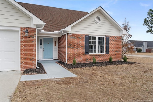 view of exterior entry featuring an attached garage, brick siding, and a shingled roof