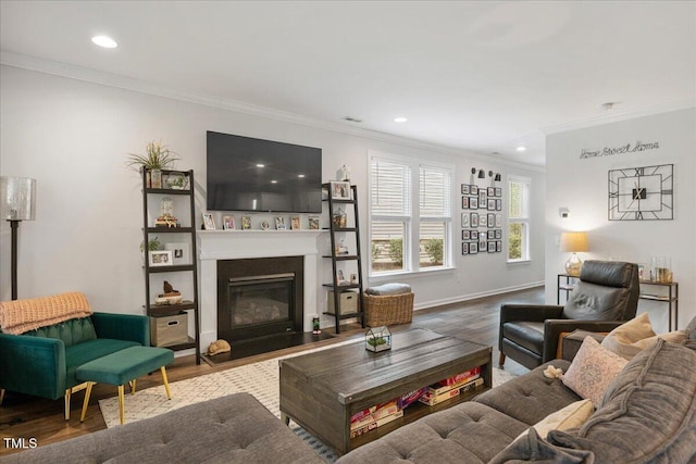 living area featuring wood finished floors, baseboards, a fireplace with flush hearth, recessed lighting, and ornamental molding