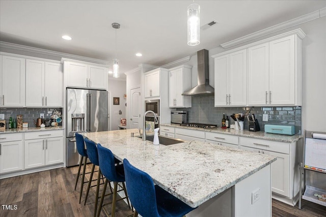 kitchen with appliances with stainless steel finishes, sink, wall chimney range hood, and white cabinets