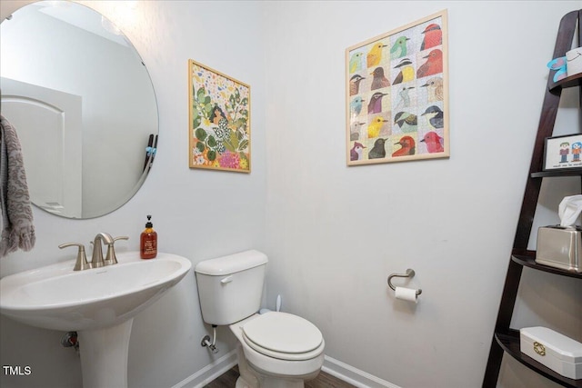 bathroom featuring toilet, baseboards, and a sink