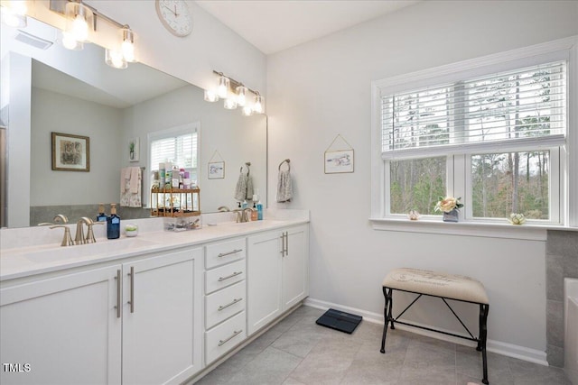 full bathroom featuring a sink, baseboards, double vanity, and tile patterned floors