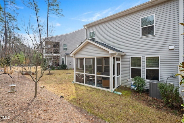 rear view of property with a sunroom, a yard, and central AC