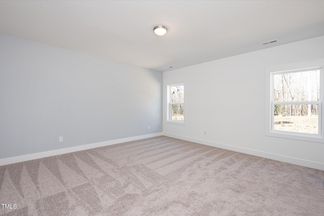 unfurnished room with baseboards, visible vents, and light colored carpet