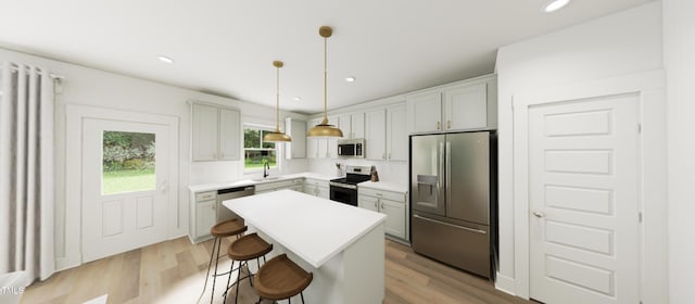 kitchen with a kitchen island, stainless steel appliances, light countertops, pendant lighting, and a sink