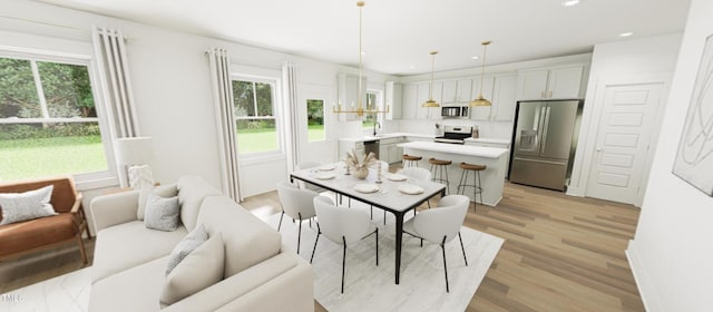 kitchen featuring pendant lighting, light countertops, appliances with stainless steel finishes, a kitchen island, and light wood-type flooring