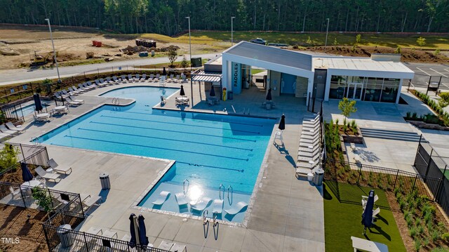 pool with fence, a view of trees, and a patio