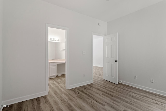 unfurnished bedroom featuring connected bathroom and light wood-type flooring