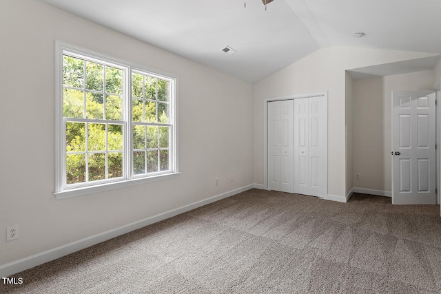 unfurnished bedroom featuring lofted ceiling, carpet, and a closet