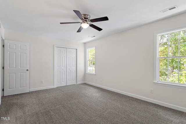 unfurnished bedroom featuring ceiling fan, a closet, carpet floors, and multiple windows