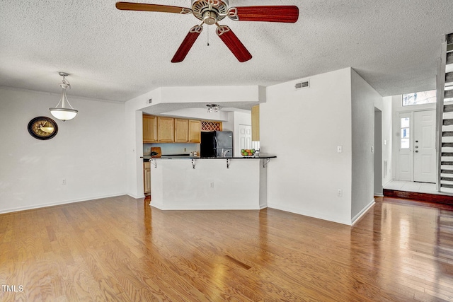 unfurnished living room featuring ceiling fan, light hardwood / wood-style floors, and a textured ceiling