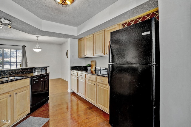 kitchen with hardwood / wood-style floors, dark stone counters, hanging light fixtures, black appliances, and a textured ceiling